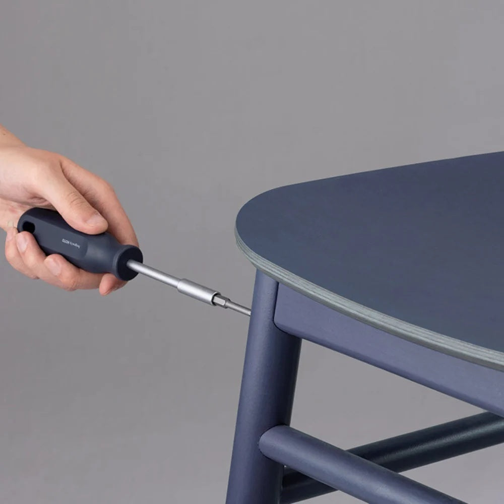 Person using a screwdriver to adjust a blue chair against a gray background