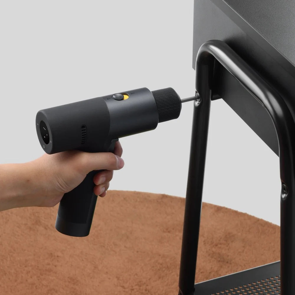 Hand using a black cordless drill to tighten a screw on a metal frame.