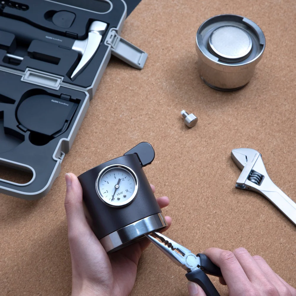 HOTO 3.6V Screwdriver Tool Set, Person holding a tool with a gauge on a corkboard background with tools.