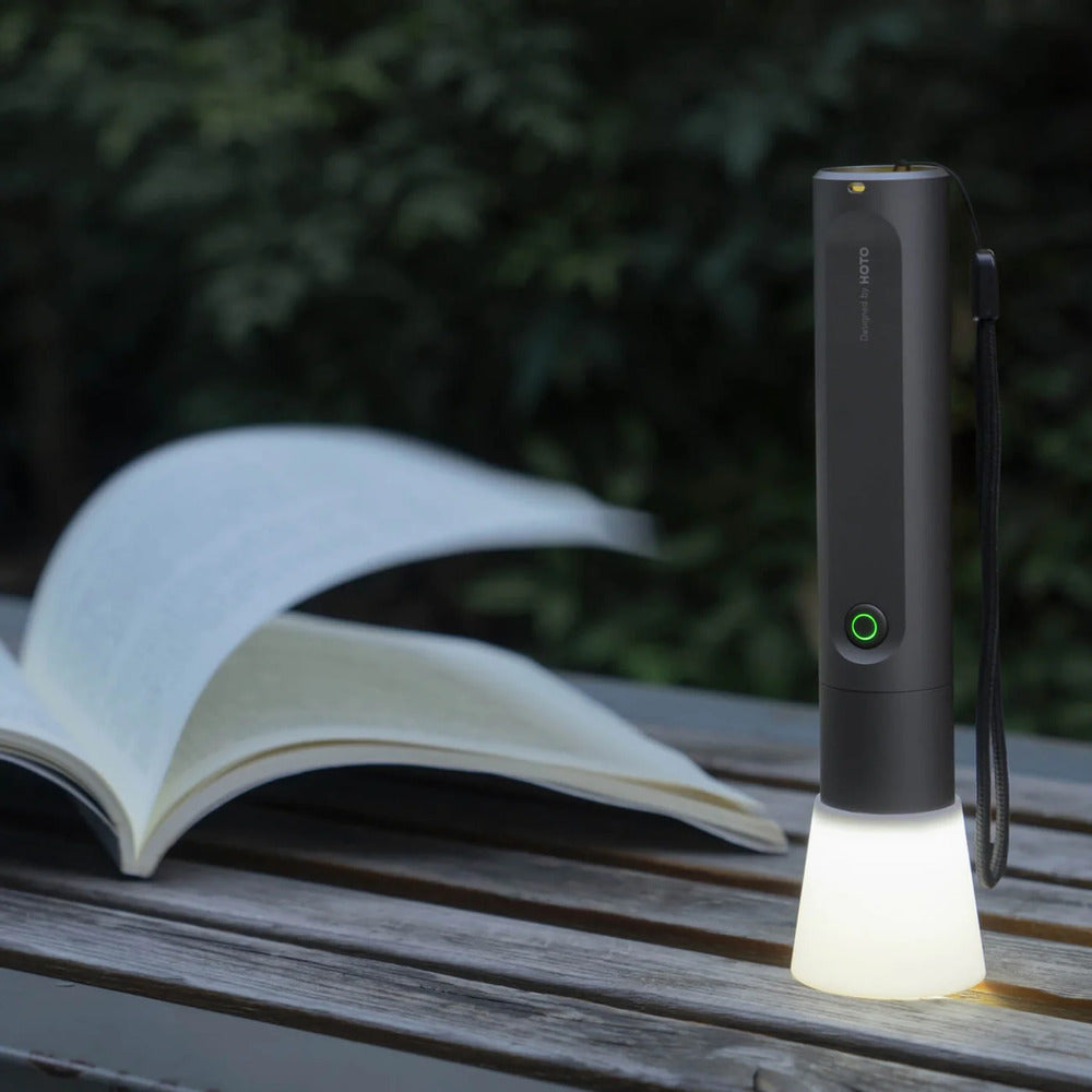 Portable flashlight on a wooden surface with an open book in the background
