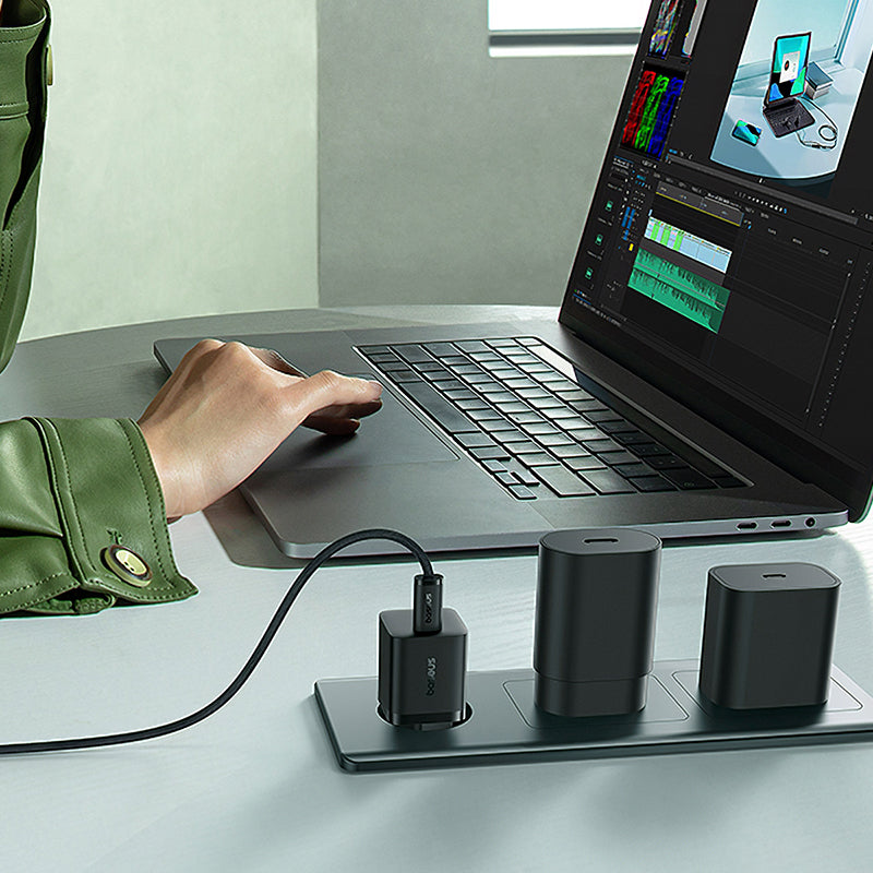 Person using a laptop with multiple devices on a desk