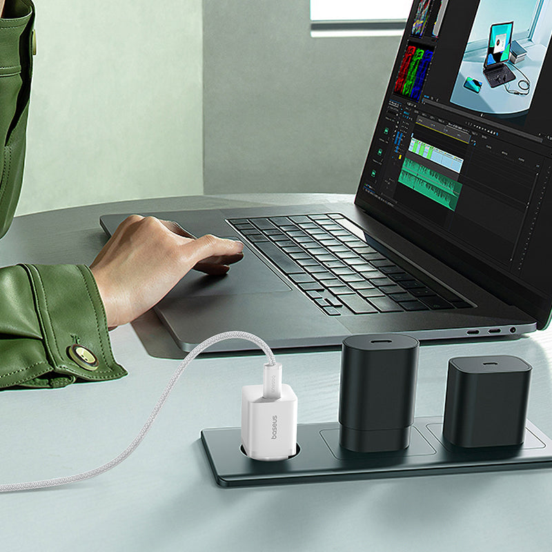 Person using a laptop with multiple devices on a desk