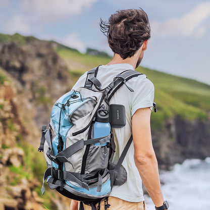 Person with a large backpack standing on a cliff overlooking a scenic landscape.