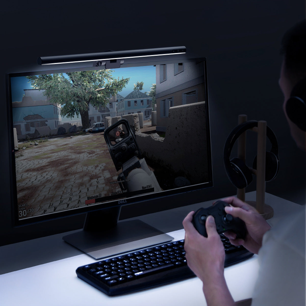 Person playing a first-person shooter game on a computer setup with a monitor, keyboard, and mouse.