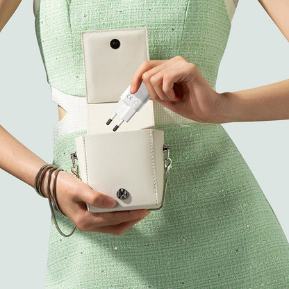 Person holding a white handbag with a pen inside, wearing a green dress.
