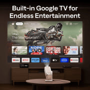 Aurzen Boom Air Portable 1080p Google TV Projector Smart TV with Google TV interface displaying various apps in a home entertainment setup.