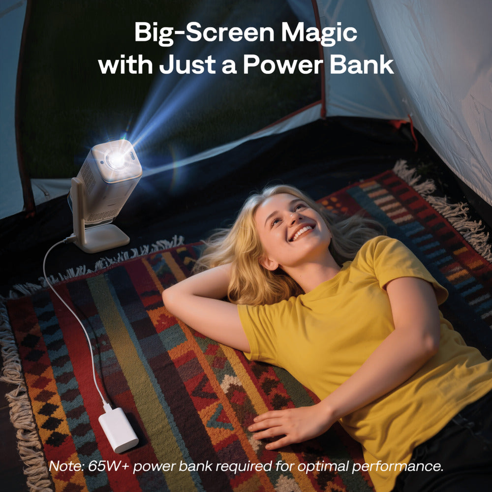 Aurzen Boom Air Portable 1080p Google TV Projector Woman lying on a rug inside a tent using a portable projector with text 'Big-Screen Magic with Just a Power Bank'.