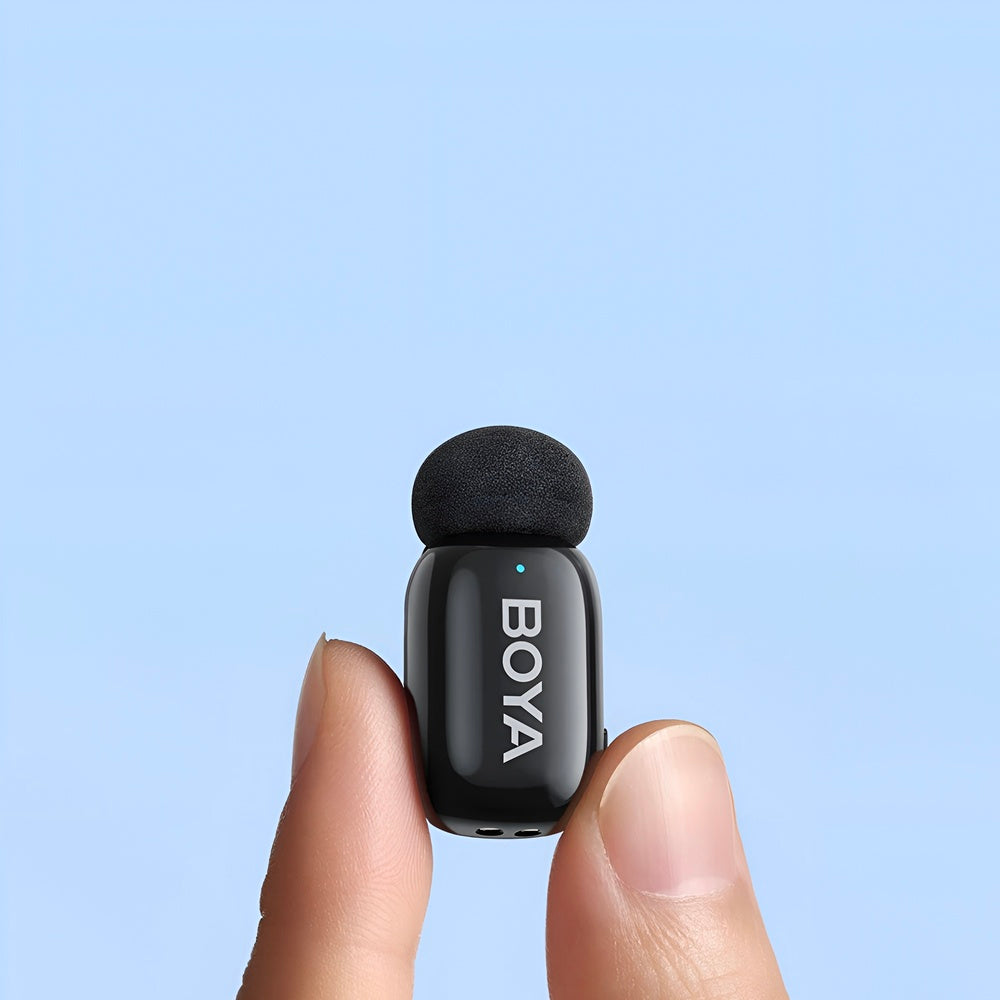 Small black microphone with 'BOYA' branding held between two fingers against a light blue background