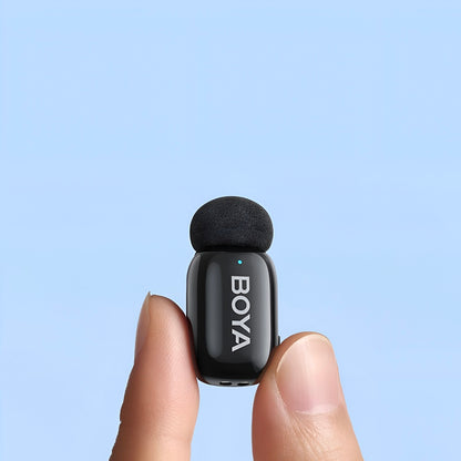 Small black microphone with 'BOYA' branding held between two fingers against a light blue background