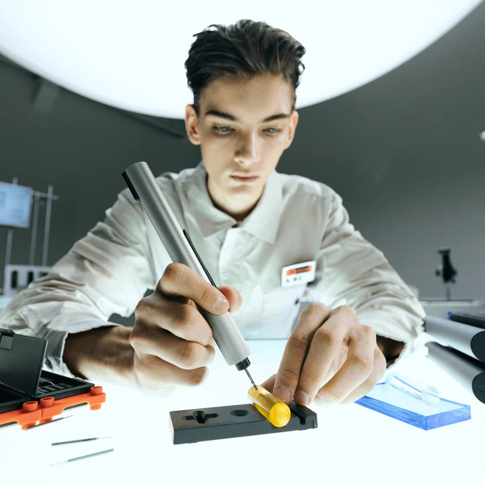 Person using a screwdriver with tools and equipment in the background