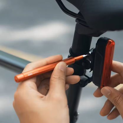 HOTO Pocket Precision Screwdriver SE Person adjusting a bike light with an orange tool on a blurred background