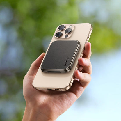 Person holding a beige phone with a magnetic case against a blurred green and blue background