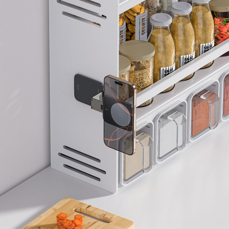Spice rack with various jars on a kitchen counter, featuring a smartphone on a stand.