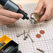 Person using a rotary tool on a grid surface with various tools and accessories.