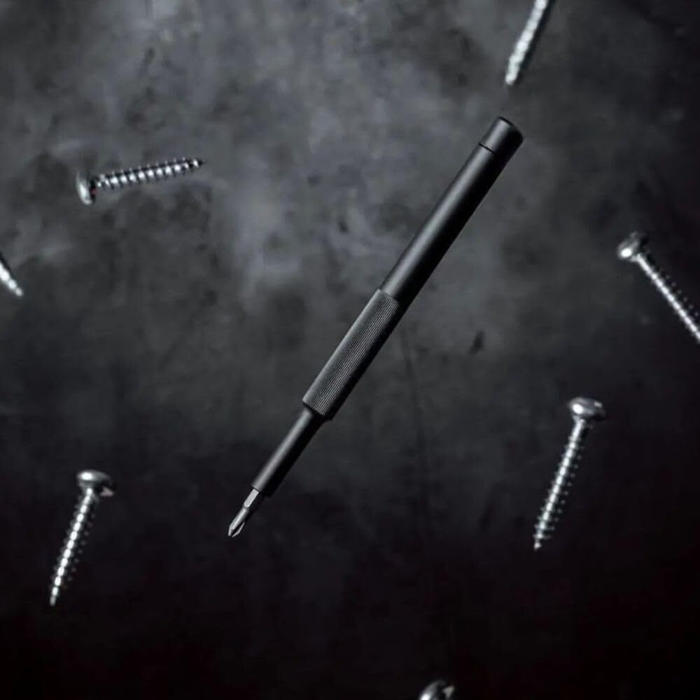 Black screwdriver on a dark textured surface with screws around it