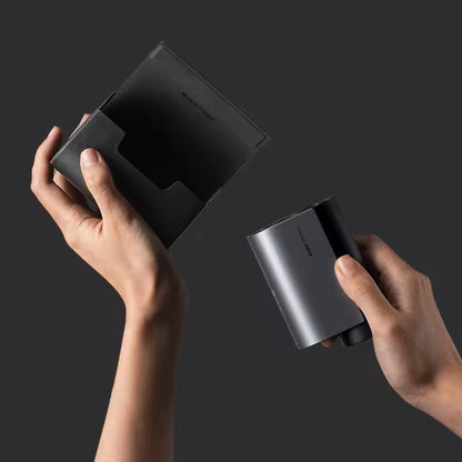 HOTO Golf Laser Rangefinder, Two hands holding a black electronic device against a dark background