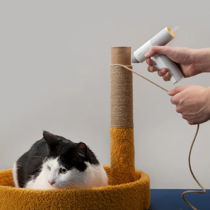 HOTO Lithium Glue Gun, Person using a hot glue gun to attach jute rope to a cat scratching post with a cat sitting below.