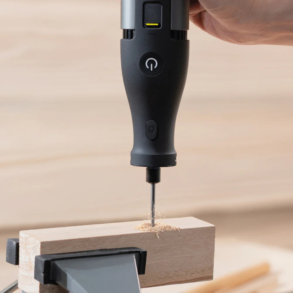 HOTO 12V Rotary Tool Kit Pro, Black handheld drill bit being used on a wooden block with a blurred background