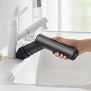 HOTO Cordless Spin Scrubber 6 Brush Head Set Hand holding a black handheld cleaning tool over a white sink with a faucet.