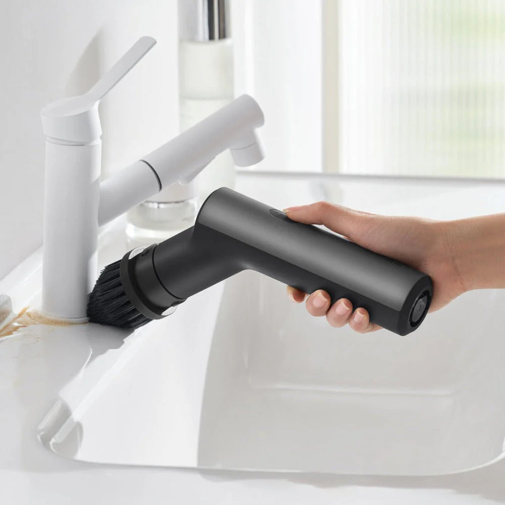 HOTO Cordless Spin Scrubber 6 Brush Head Set Hand holding a black handheld cleaning tool over a white sink with a faucet.
