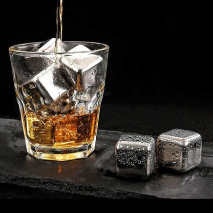 Glass of whiskey with ice cubes and metal stones on a dark surface