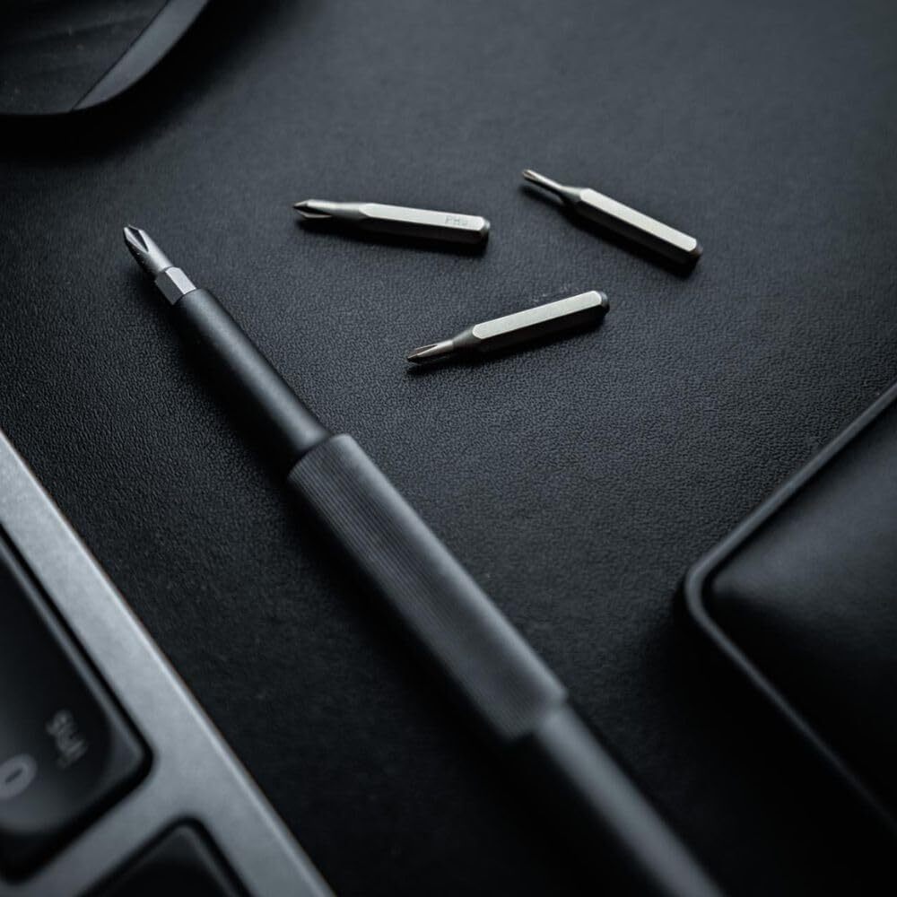 Black screwdriver set with multiple drill bits on a dark surface