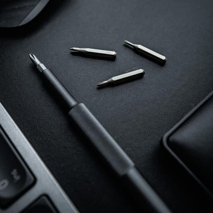 Black screwdriver set with multiple drill bits on a dark surface