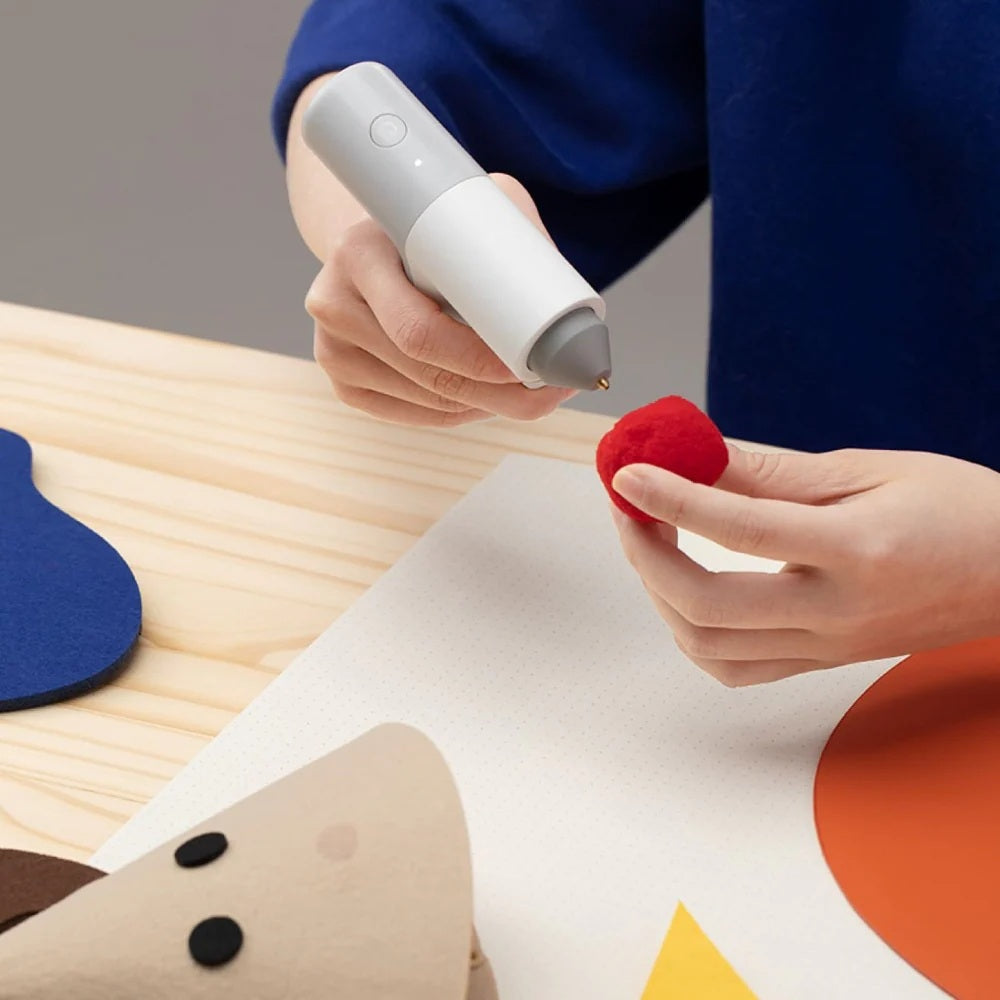 HOTO Lithium Glue Gun, Person using a white tool on a red object with a colorful background