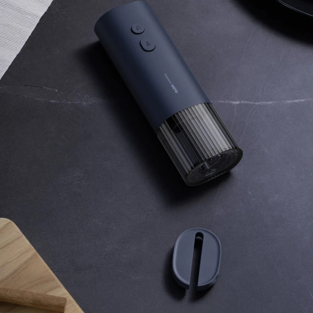HOTO Electric Wine Opener .Dark blue electronic device on a dark surface with a wooden edge.