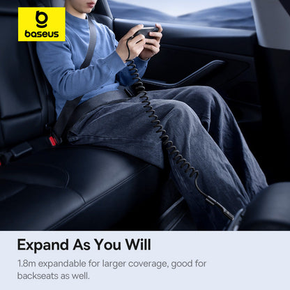 Person sitting in a car with a device connected by a coiled cable, Baseus logo visible.