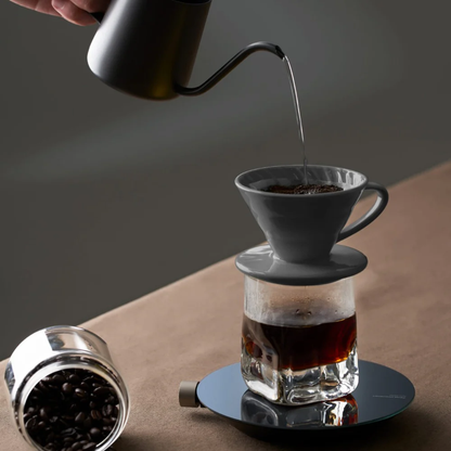 HOTO Smart Kitchen Scale, Hand pouring coffee from a kettle into a glass carafe with a coffee filter on a wooden surface.