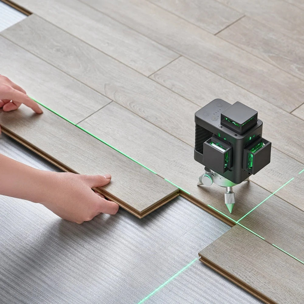 Laser level device on a wooden floor with green lines, used for alignment.