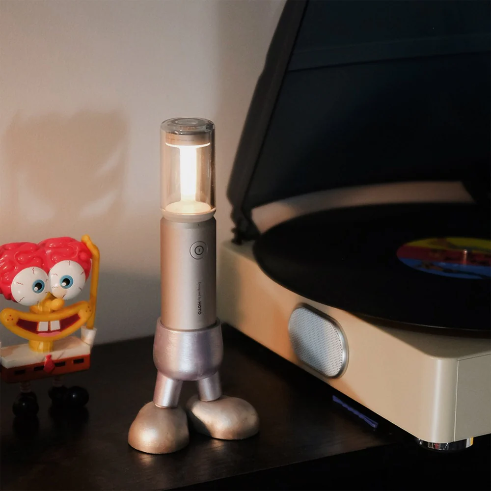 Silver robot-like lamp on a table next to a record player and SpongeBob toy.