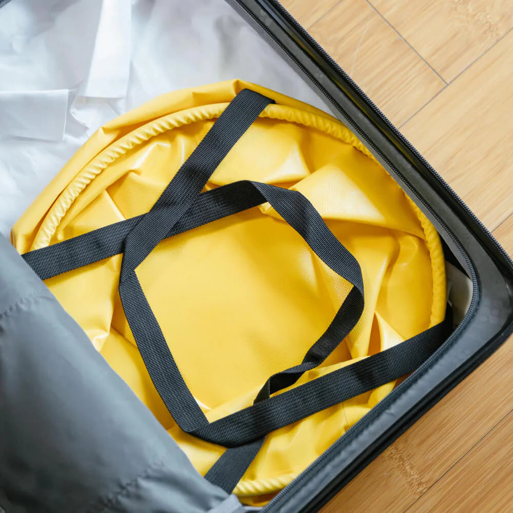HOTO Outdoor Wash Kit, Yellow bag with black straps inside an open suitcase on a wooden floor.