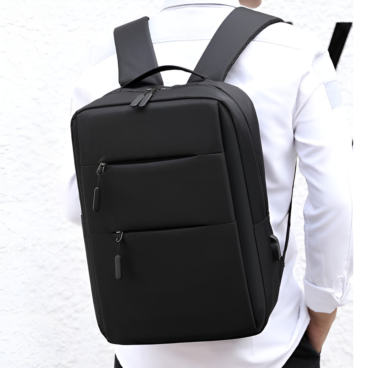 Black backpack worn by a person on a white background