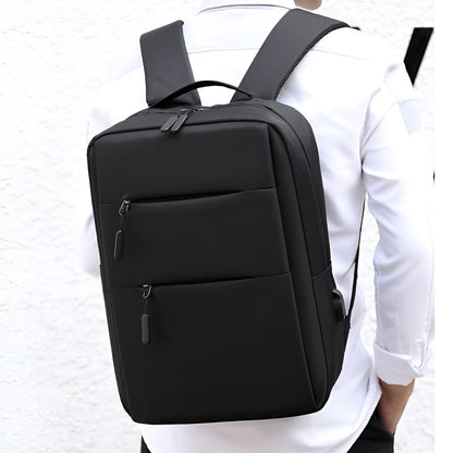 Black backpack worn by a person on a white background