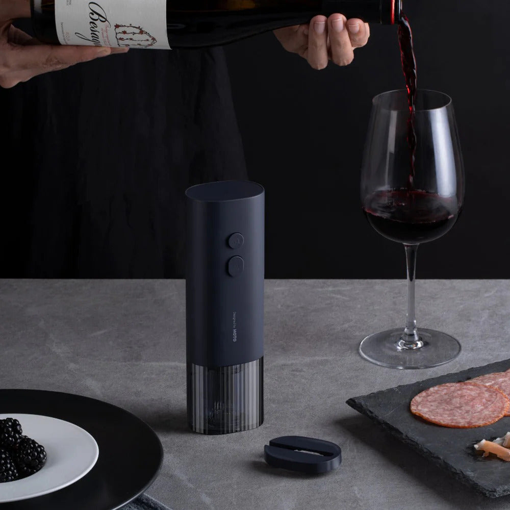 HOTO Electric Wine Opener. Wine being poured into a glass with a wine bottle opener on a table.
