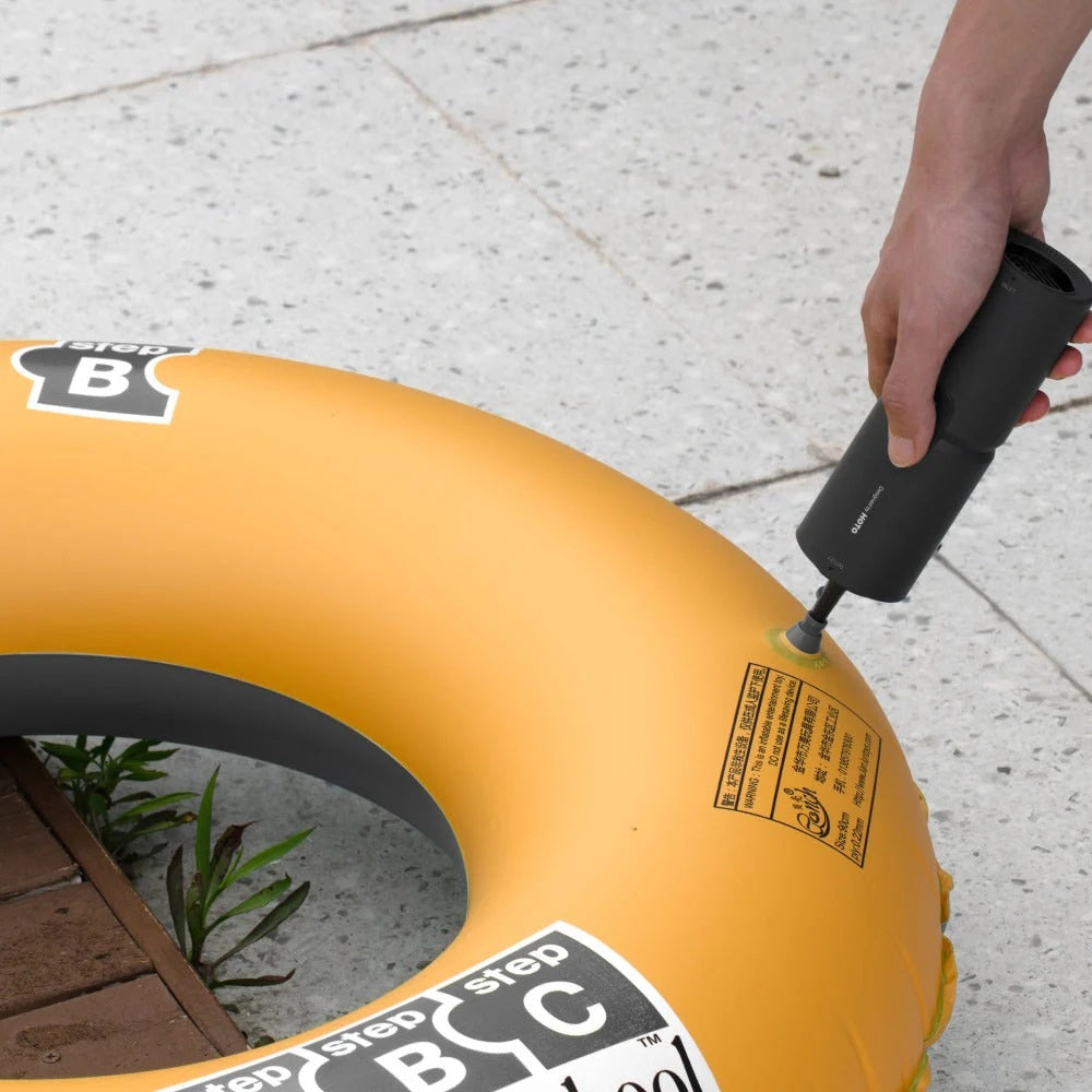 HOTO Compressed Air Capsule ,Person inflating a yellow inner tube with a black pump on a concrete surface.