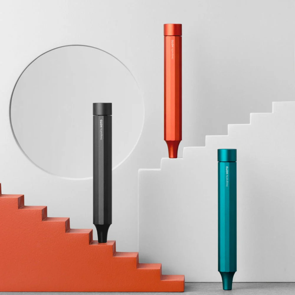 Three cylindrical products in black, red, and teal on a white staircase with a gray background.