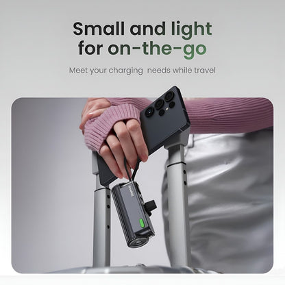 Sharge Flow Mini 2 22.5W Power Bank (5000mAh, Built‑in USB‑C & Lightning) Hand holding a smartphone with a charging device attached, on a travel bag background.