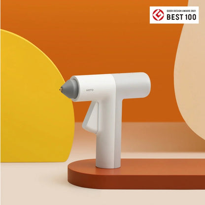 HOTO Lithium Glue Gun, White handheld device with gray nozzle on an orange and yellow background, featuring the Good Design Award 2021 Best 100 logo.