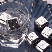 Metallic ice cubes in a glass of water on a reflective surface