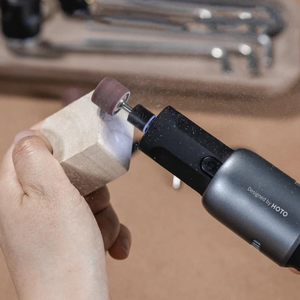 Hand using a HOTO power tool on a wooden block with a blurred background