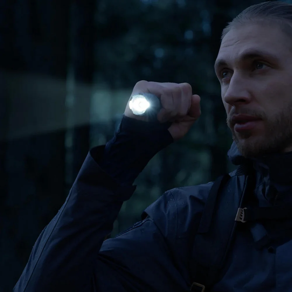 HOTO Flashlight Tactics 2300 Tactical Rechargeable Torch Person holding a flashlight in the dark outdoors