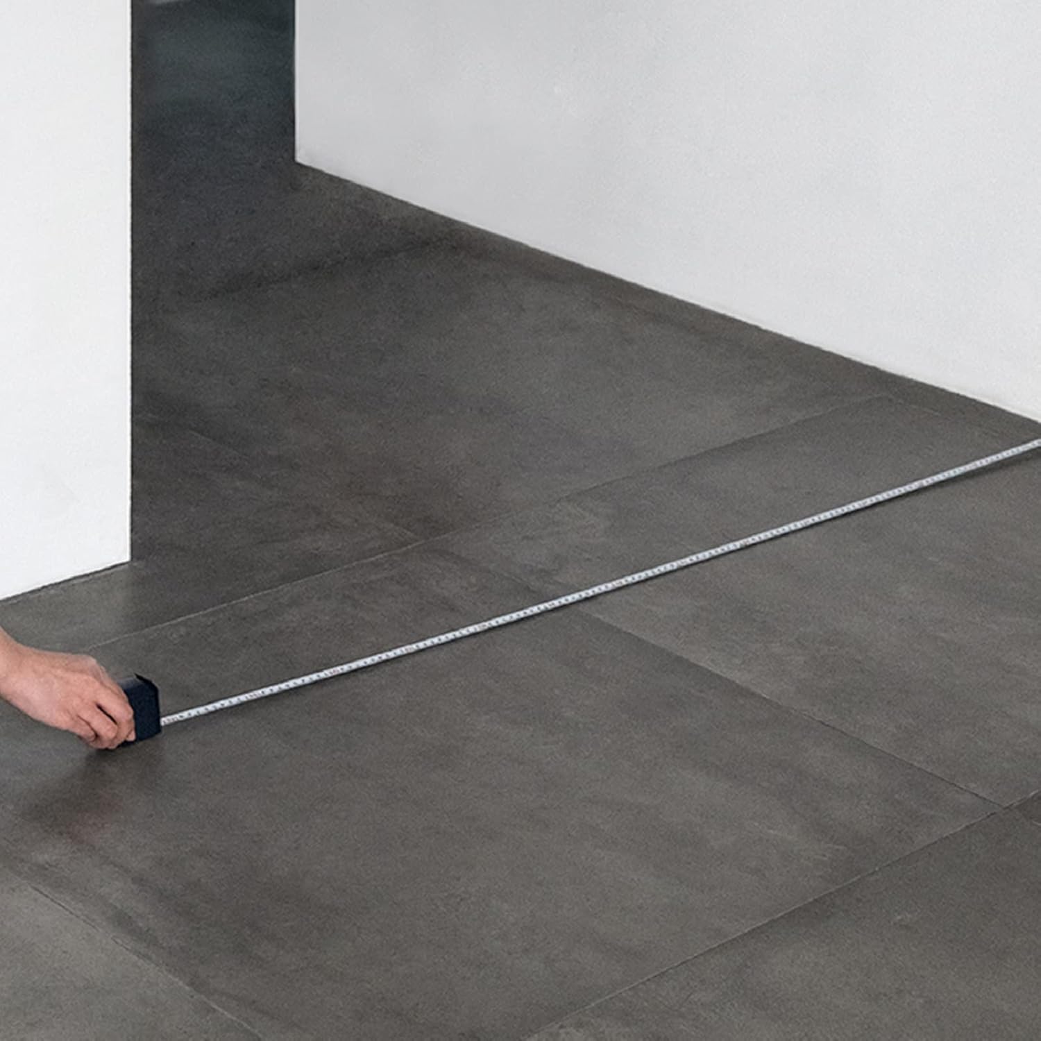 HOTO Self-locking Tape Measure, Person measuring a large sheet of gray tiles with a tape measure.