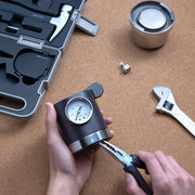 HOTO Household Tool Kit Multipurpose Set Person using a tool with a gauge on a wooden surface with tools and equipment.