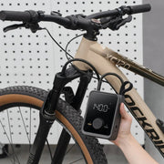 HOTO Air Pump Pro Portable Tire Inflator 120 PSI Bicycle with a power meter attached to the handlebar, against a white pegboard background.