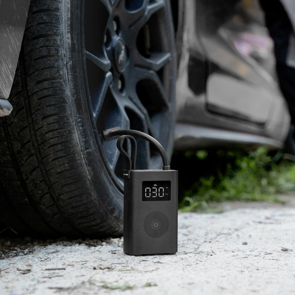 HOTO Electric Air Pump, Portable air compressor next to a car tire on a gravel surface