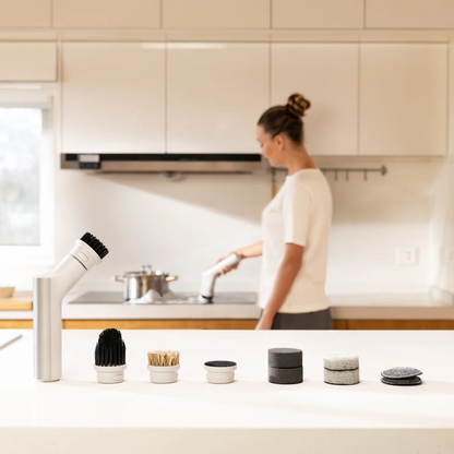 Woman in a kitchen with various cleaning tools on the counter