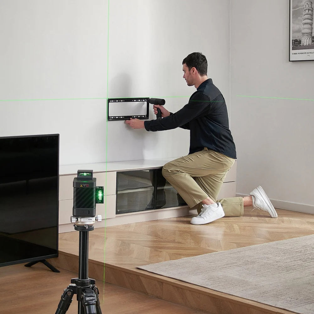 Person using a laser level to measure wall height in a room with a TV and rug.